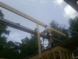 Carpenter setting a ridge beam over a new addition frame — Ice Dam Removal by Roofing Brothers in Millbrook